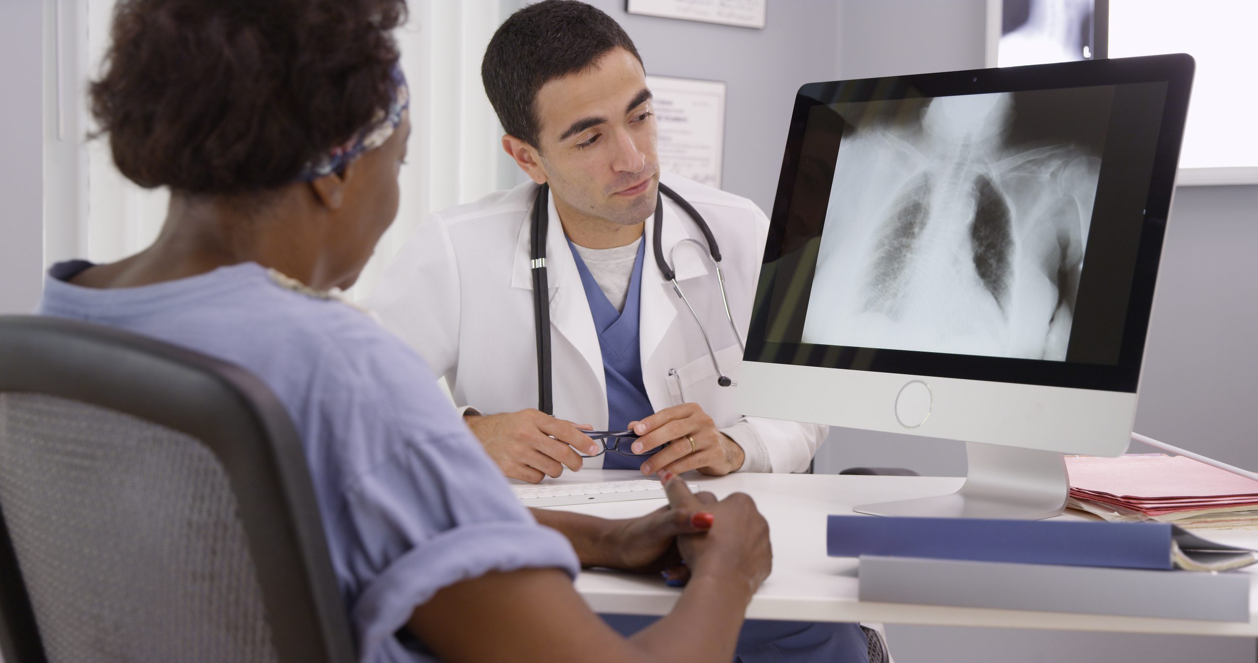 Old African patient paying doctor visit to review results from x-rays of lungs